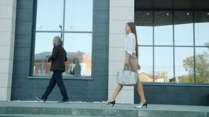 Žena u poslovnoj kombinaciji sa svetlom torbom srednje veličine i cipelama na potpeticu, elegantan dnevni look.