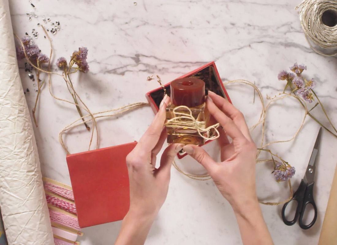 prikaz osobe koja pakuje parfem u kutiju za poklon